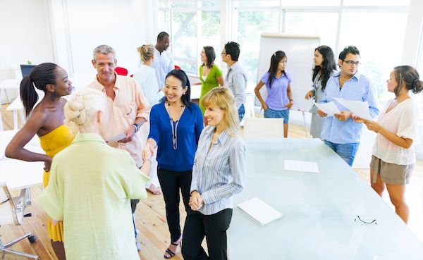 A facilitator at a flip chart leading a seated group through a discussion.