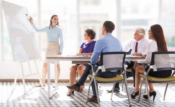 A diverse group of colleagues laughing and talking in a bright, open training room.